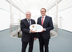 Staatssekretär im bayerischen Sozialministerium, Johannes Hintersberger, überreicht das Emblem „Inklusion in Bayern – wir arbeiten miteinander“ (Foto)